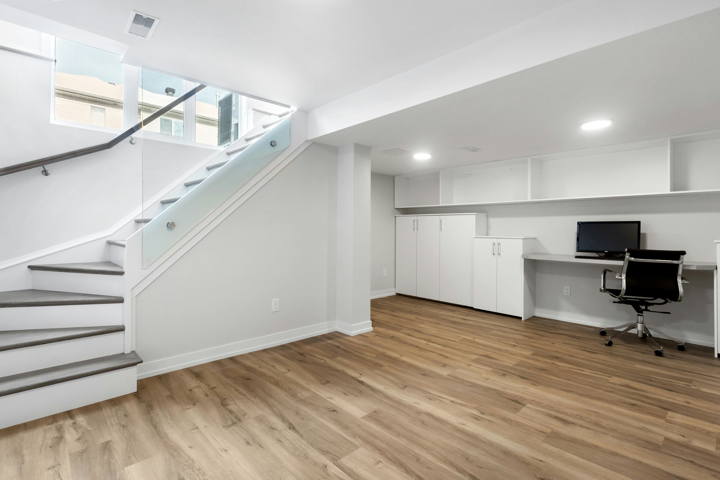 A finished basement with a light plank floor